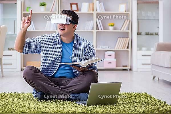 Freelance student with virtual reality glasses at home [IBR125062235]