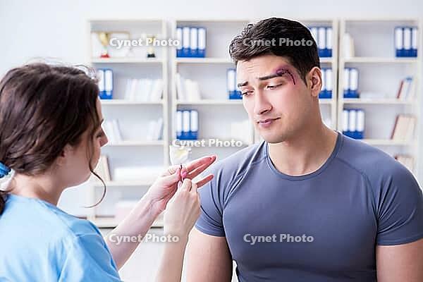 Young man visiting female traumatologist with black eye [IBR125062241]