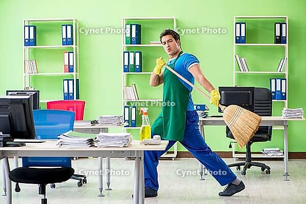 Young male handsome professional cleaner cleaning floor with broom [IBR125062244]