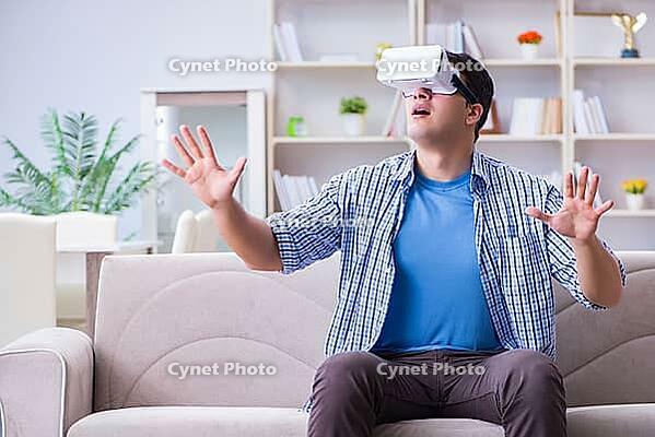 Man with virtual reality glasses playing at home [IBR125062246]
