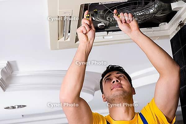 Repairman repairing ceiling air conditioning unit [IBR125062250]
