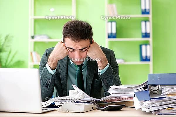 Businessman angry with excessive work sitting in the office [IBR125062255]