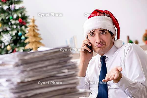Young worker working in office on christmas shift [IBR125075735]