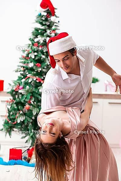 Young pair celebrating christmas at home [IBR125075747]
