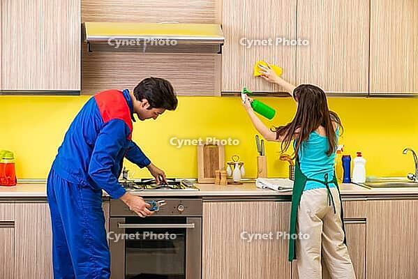 Woman with contractor at kitchen discussing repair [IBR125075749]