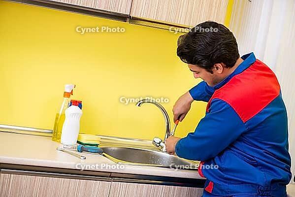 Plumber repairing tap at kitchen [IBR125075750]