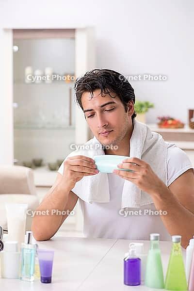 Young handsome man in the bathroom in hygiene concept [IBR125075753]