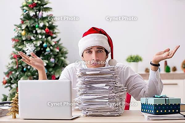Young worker working in office on christmas shift [IBR125075758]