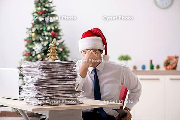 Young worker working in office on christmas shift [IBR125075759]