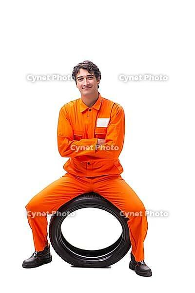 Young garage worker with tyre isolated on white [IBR125075787]