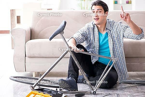 Young man repairing bicycle at home [IBR125094346]