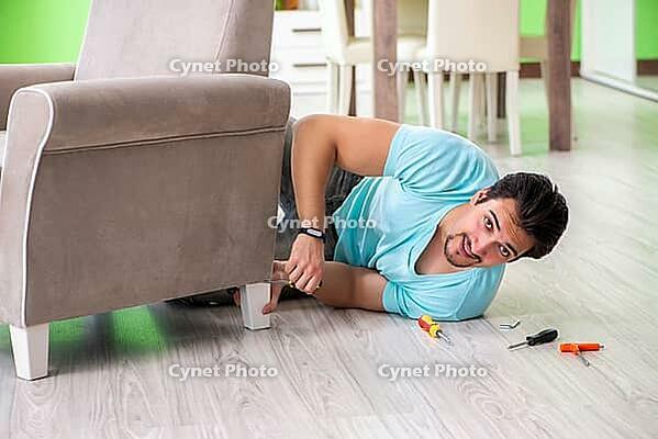 Man repairing furniture at home [IBR125094357]