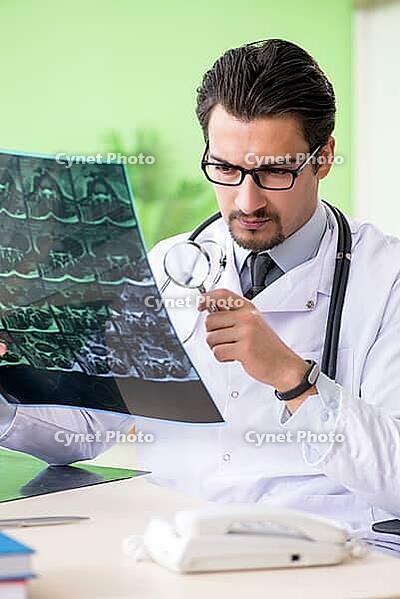 Doctor radiologist looking at x-ray scan in hospital [IBR125094372]