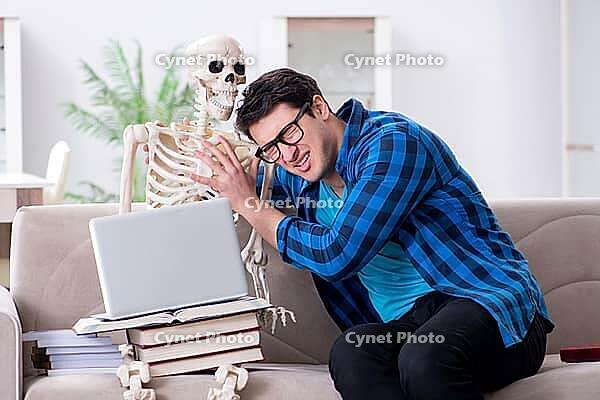 Student studying with skeleton preparing for exams [IBR125094381]