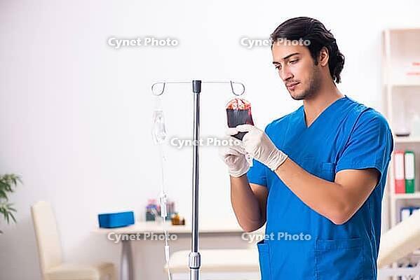 Young male doctor in blood transfusion concept [IBR125117993]
