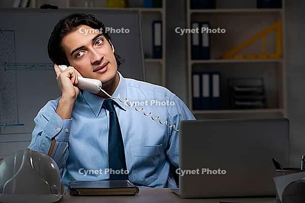 Young male architect working night at office [IBR125117998]
