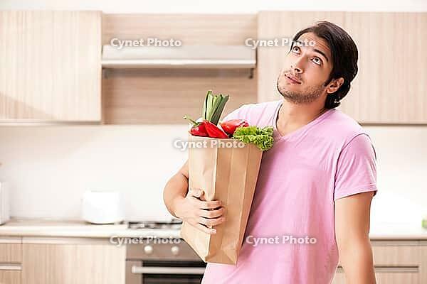 Young handsome man with vegetables in the kitchen [IBR125117999]