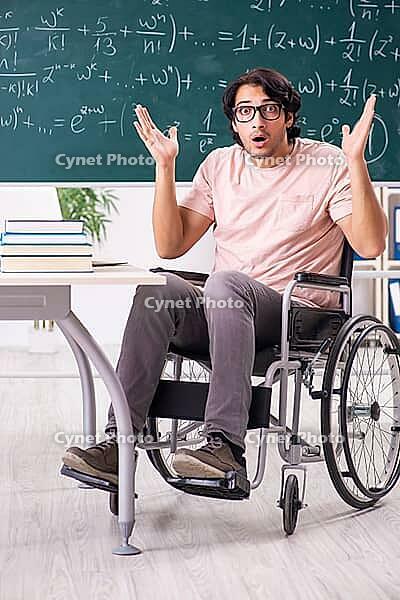 Young handsome man in wheelchair in front of chalkboard [IBR125118002]