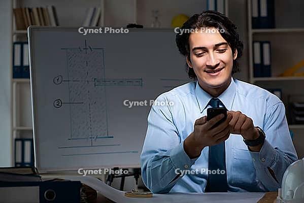 Young male architect working night at office [IBR125118030]