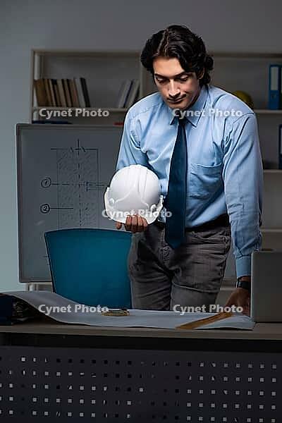Young male architect working night at office [IBR125118031]