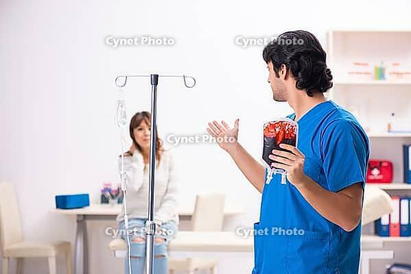 Young male foctor and female patient in blood transfusion concept [IBR125118037]