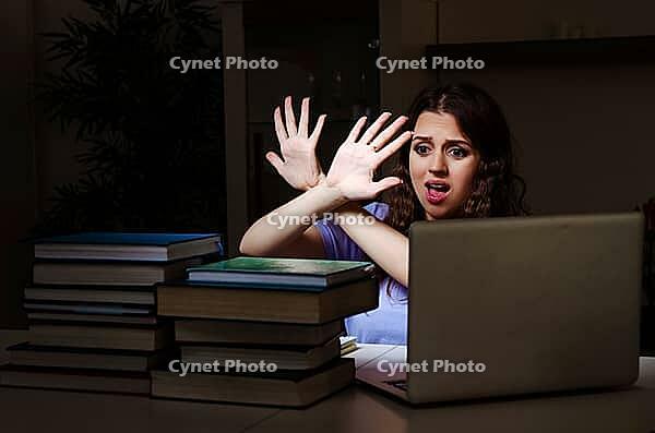 Young female student preparing for exams late at home [IBR125141693]