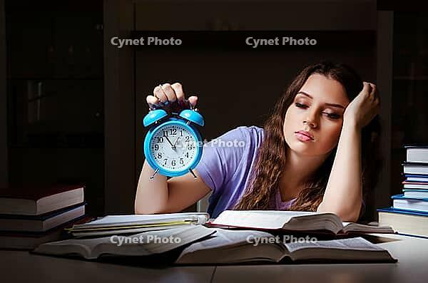 Young female student preparing for exams late at home [IBR125141695]