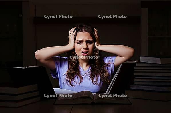 Young female student preparing for exams late at home [IBR125141698]