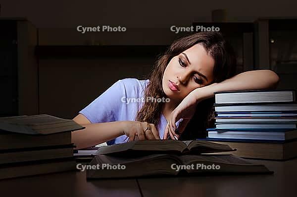 Young female student preparing for exams late at home [IBR125141700]