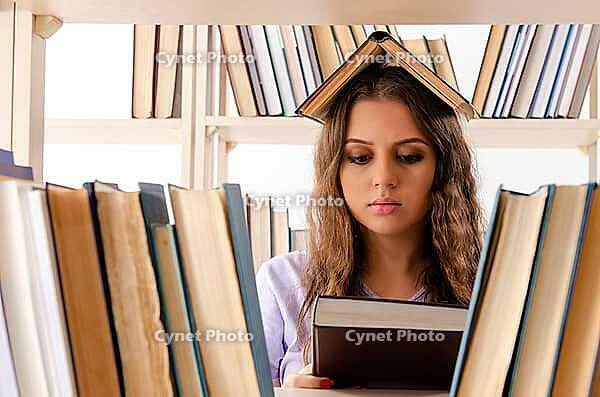 Young female student preparing for exams at library [IBR125141701]