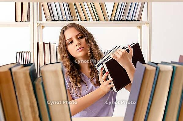 Young female student preparing for exams at library [IBR125141702]