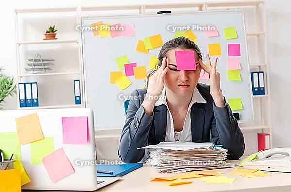 Young female employee in conflicting priorities concept [IBR125141704]