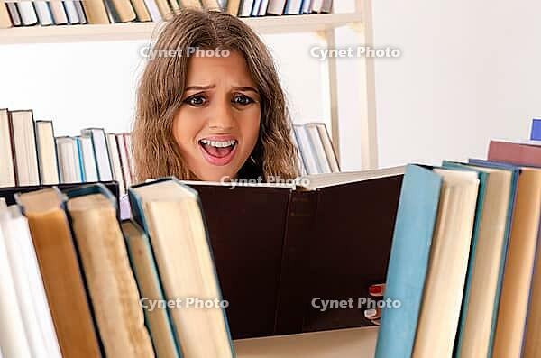 Young female student preparing for exams at library [IBR125141705]
