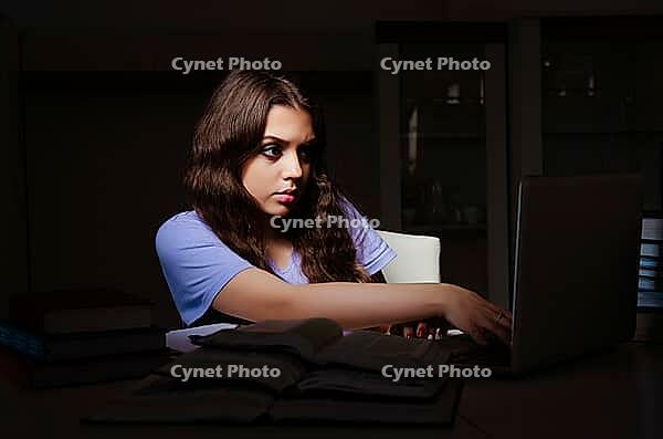 Young female student preparing for exams late at home [IBR125141708]