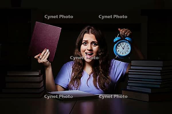 Young female student preparing for exams late at home [IBR125141710]