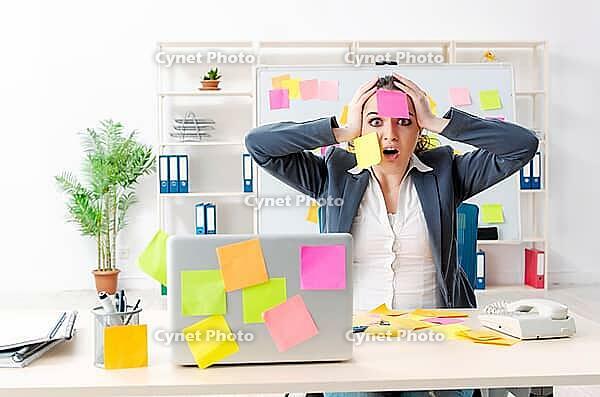 Young female employee in conflicting priorities concept [IBR125141713]