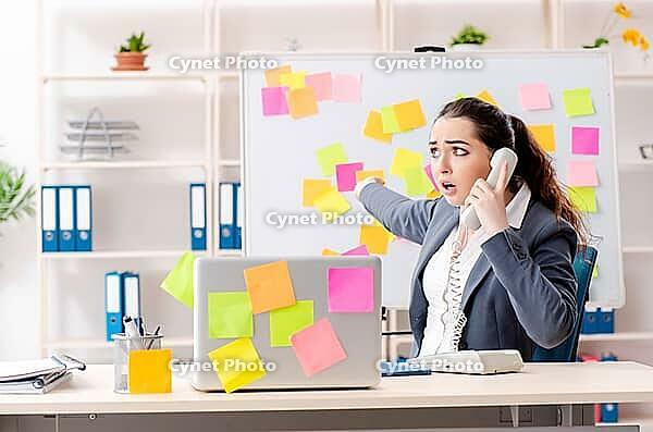 Young female employee in conflicting priorities concept [IBR125141715]