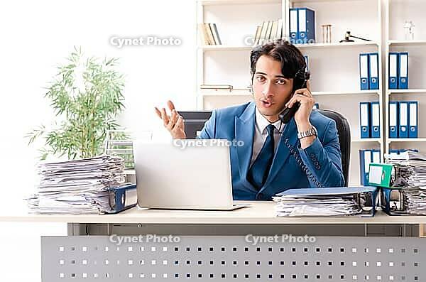 Young handsome busy employee sitting in office [IBR125141730]