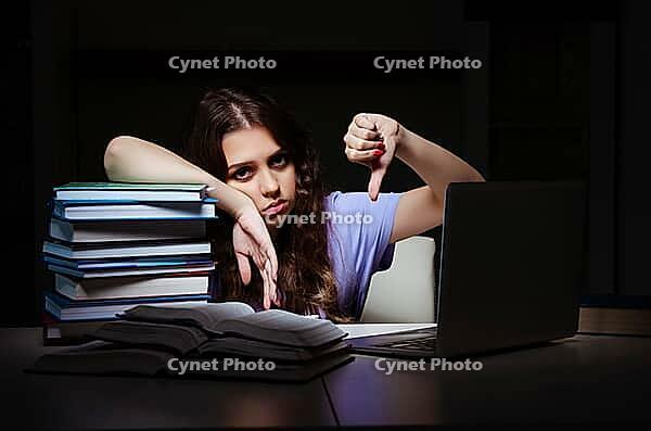 Young female student preparing for exams late at home [IBR125141746]