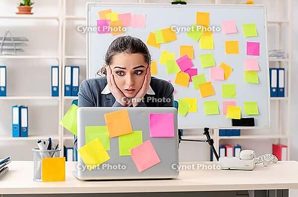 Young female employee in conflicting priorities concept [IBR125141749]