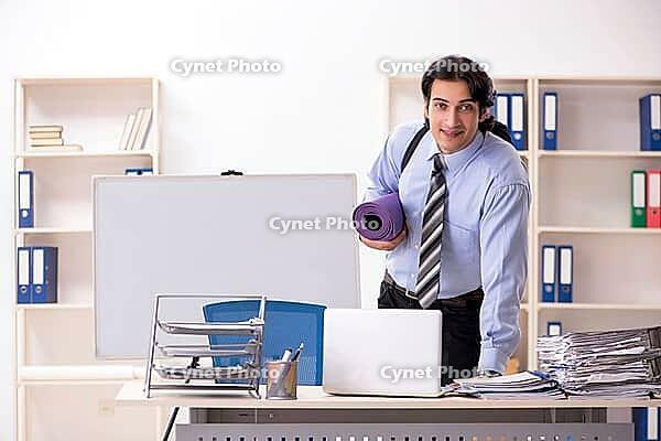 Young handsome male employee doing exercises in the office [IBR125141755]