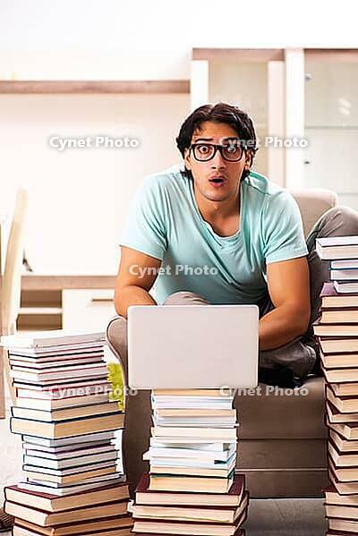 Male student with many books at home [IBR125141765]