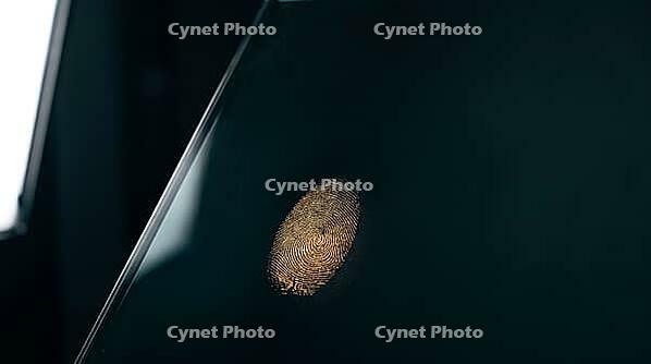 Latent fingerprint friction ridge detail revealed by raking sidelight on dark glass surface, amber luminous ridge lines against teal-black background, forensic crime scene investigation concept, studio shot, AI generated [IBR125167457]