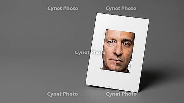 Passport-format identity photograph card showing morphed composite face, two different faces joined at vertical centerline, face morphing identity fraud concept, grey background, studio shot, AI generated [IBR125167460]