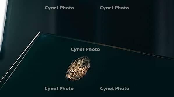 Latent fingerprint friction ridge detail revealed by raking sidelight on dark glass surface, amber luminous ridge lines against teal-black background, forensic crime scene investigation concept, studio shot, AI generated [IBR125167463]