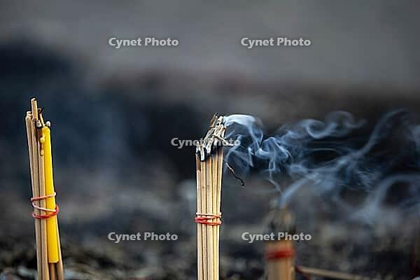 Fine smoke rises between the upright incense sticks and forms soft, swirling lines in the warm air. The bundles are carefully tied and depict a serene scene of traditional offerings such as those found in many temples and shrines, Wat Yai Chai Mongkon, Ay [IBR125177957]