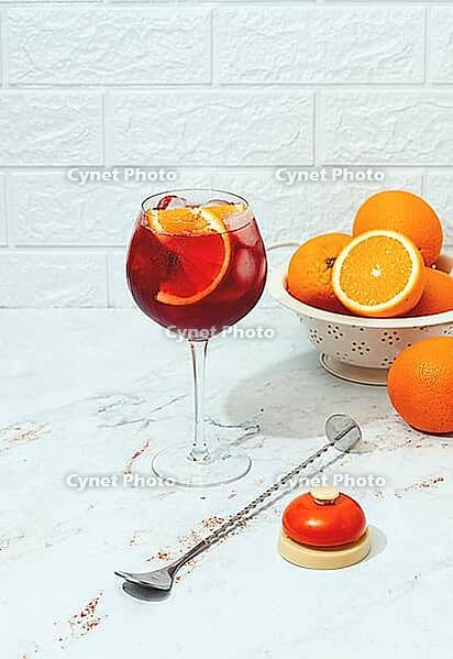 Making an Aperol cocktail, with a colander of oranges in the background, a bottle of Aperol, a cocktail spoon, and a bartender's bell, there are no people [IBR125178023]