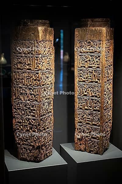 Antique Islamic wooden panels with Arabic calligraphy and geometric carvings exhibited in museum setting [IBR125180371]
