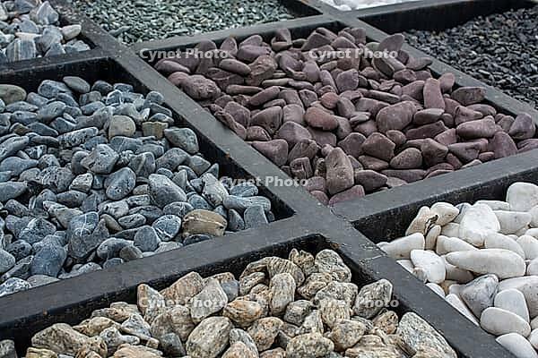 Collection of assorted decorative landscaping stones, gravel, and pebbles arranged in a sample box [IBR125180378]