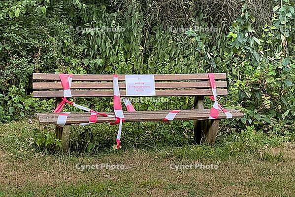 Wooden bench in nature with barrier tape and warning sign on oak procession spinner, Guxhagen, Hesse, Germany [IBR125180388]